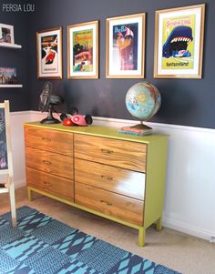 there is a dresser in the room with pictures on the wall and a globe on top