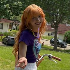 a woman with long red hair standing next to a bike