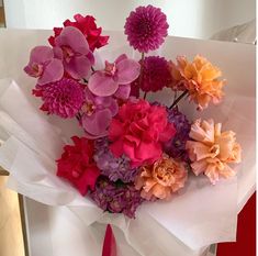 a bunch of flowers that are on top of a white sheet with pink and orange flowers