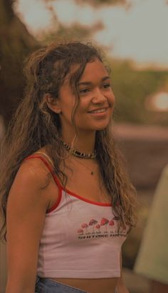 a woman with long hair wearing a white shirt and jeans is smiling at the camera