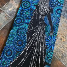 a blue and black painting on a tile floor with a woman in a long dress