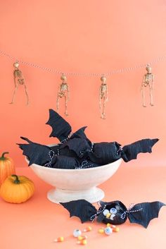 halloween decorations in a white bowl with skeleton figurines hanging from the line above them