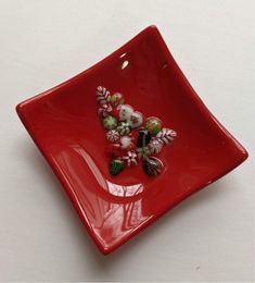 a red square plate with flowers and leaves on the edge, sitting on a white surface