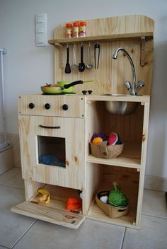 a wooden toy kitchen with lots of cooking utensils