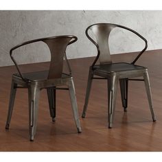 two metal chairs sitting on top of a wooden floor