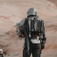 a man with a backpack on his back standing in the desert