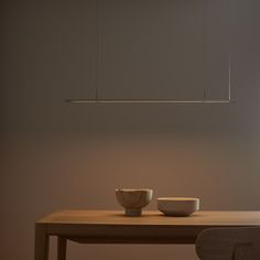 two bowls sit on a table in front of a suspended light