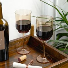 two wine glasses and a cork on a tray