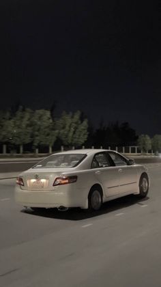 a white car driving down the road at night