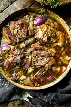 a pot filled with meat and vegetables on top of a wooden table