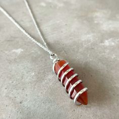 Introducing our one-of-a-kind Carnelian Spiral Wrapped Pendant Necklace by ASANA! This unique piece is handmade with natural carnelian stones and features a beautiful spiral design. The necklace is adjustable, so you can wear it at whatever length you choose. Carnelian necklace is known for its energies of motivation and courage, making it the perfect stone to wear when you need an extra boost.

 	Size: 18 inches
 	Free Shipping 2 Days
 	Authentic Stone Carnelian Adjustable Wire Wrapped Carnelian Necklace, Adjustable Carnelian Necklace Hand Wrapped, Adjustable Hand Wrapped Carnelian Necklace, Adjustable Amber Carnelian Crystal Necklaces, Carnelian Crystal, Carnelian Necklace, Carnelian Pendant, Carnelian Stone, Meaningful Jewelry