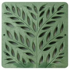 a green metal plate with leaves cut out on the front and back of it's surface