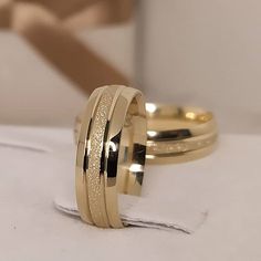 two gold wedding rings sitting on top of each other