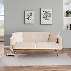 a white couch sitting on top of a hard wood floor next to a book shelf