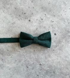 a green bow tie sitting on top of a cement floor next to a white wall