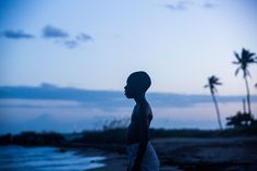 a man standing on top of a beach next to palm trees