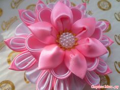 a pink flower with pearls on it sitting on top of a white cloth covered table