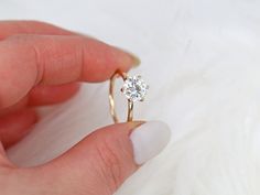 a person is holding a diamond ring in their hand