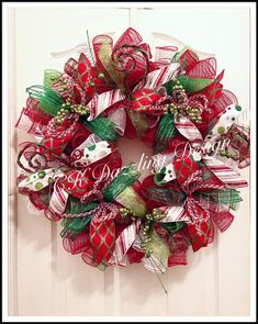 a red and green christmas wreath hanging on a door