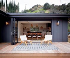 two chairs sitting on top of a wooden deck next to a table and chair set