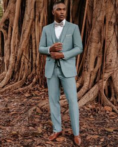 a man in a blue suit standing next to a tree