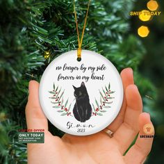 a hand holding a christmas ornament with a black cat on it