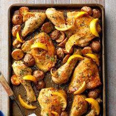 chicken with lemons and mushrooms in a baking dish on a wooden table next to a spatula