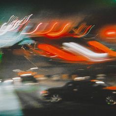 blurry photograph of cars driving down the road at night time with lights in the background