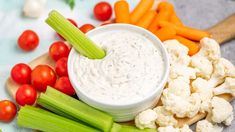 celery, carrots, and cauliflower are arranged on a cutting board