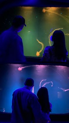 two people looking at an aquarium with jelly fish in it