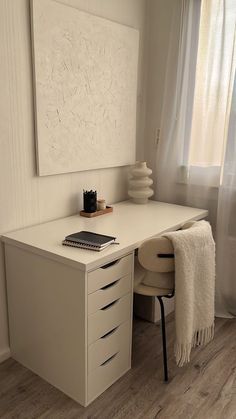 a white desk sitting next to a window with a painting on the wall above it