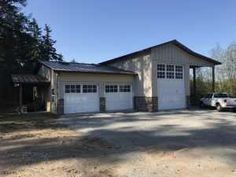 a white truck is parked in front of a large house with two garages on each side