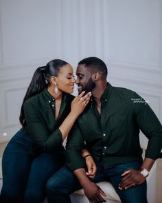 a man and woman sitting on top of each other in front of a white wall