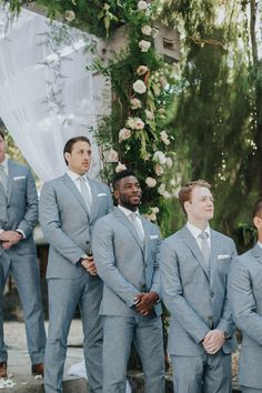 a group of men in suits standing next to each other under a wedding chute