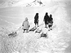 four people are walking in the snow with skis and sleds behind them