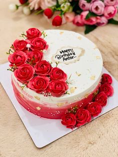 a white and red cake with roses on it