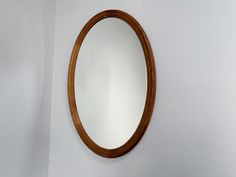 an oval wooden mirror hanging on the wall