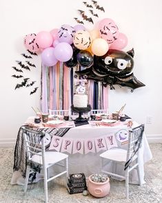 a table topped with balloons and decorations for a spooky halloween birthday party in pink, black and white