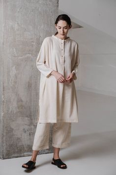 Flowy off-white dress constructed with handwoven cotton from kachchh. it has a round button down the neck hidden side pockets quarter sleeves and loose-fit ideal for formal meetings office wear or casual suppers. Minimal Fits, Cod Set, Off White Dresses, Oversized Tunic, Round Button, Indian Attire, Stylish Dress Designs, Kurti Designs, Office Wear