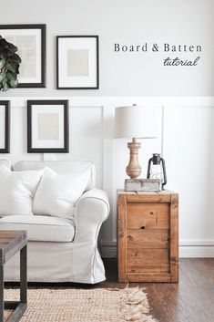 a living room with white furniture and pictures on the wall