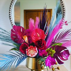 a vase with flowers and feathers in front of a mirror