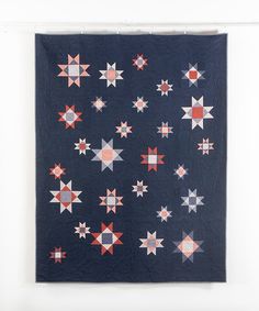 a quilted wall hanging with red, white and blue stars in the center on it