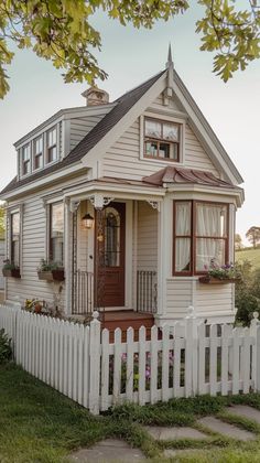 a small white house with a picket fence around the front door and windows on each side