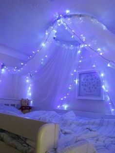 a bed with white sheets and lights on it