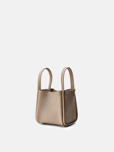 a beige handbag on a white background with the handle extended to it's side