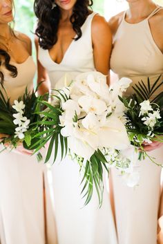 the bridesmaids are holding their bouquets with white flowers in them and greenery