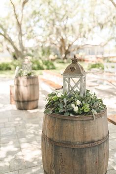 a wooden barrel with flowers and a lantern on top sits in the middle of a walkway