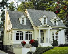 a white house with two story windows and flowers in the window boxes on the front