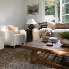 a living room filled with furniture and a wooden table in front of a large window