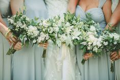 the bridesmaids are holding their bouquets with white and green flowers on them